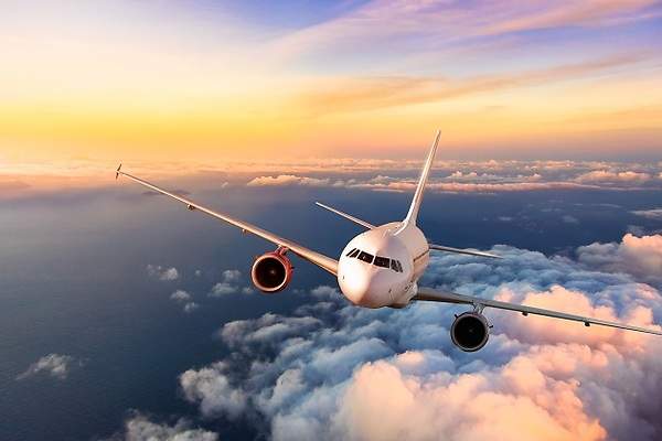 Airplane flying above the clouds at sunset.