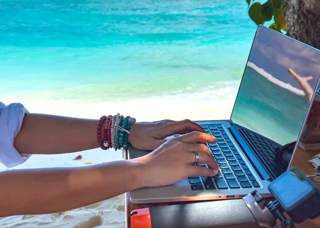 Person working on laptop by the beach.