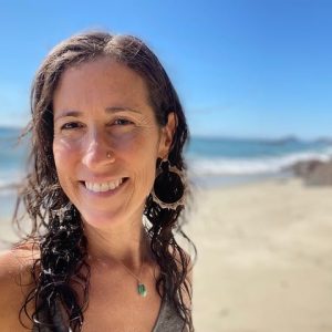 Woman smiling on beach, wearing earrings.